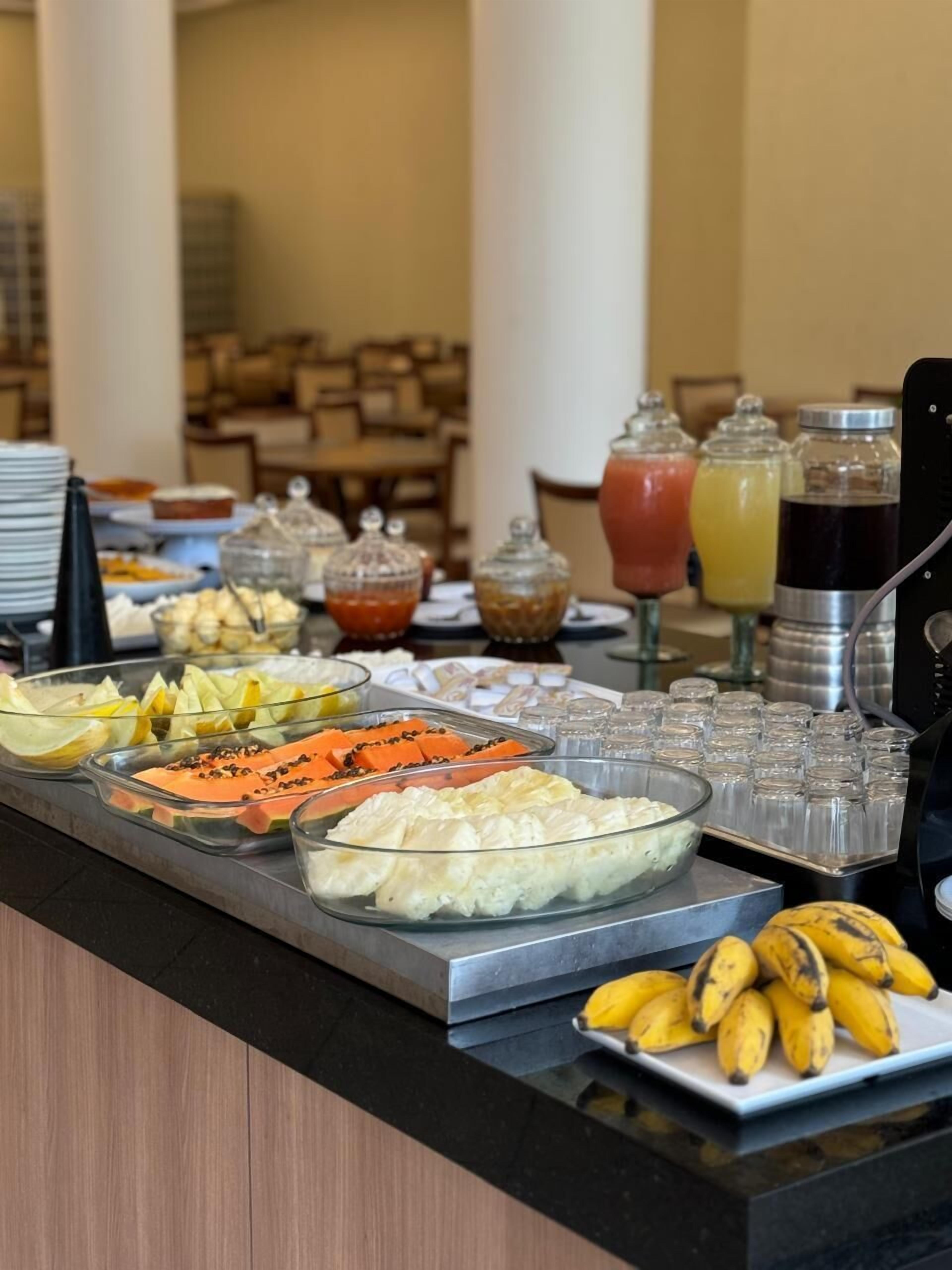 Buffet com diversos alimentos, incluindo frutas, queijos e bebidas.