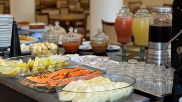 Buffet com diversos alimentos, incluindo frutas, queijos e bebidas.