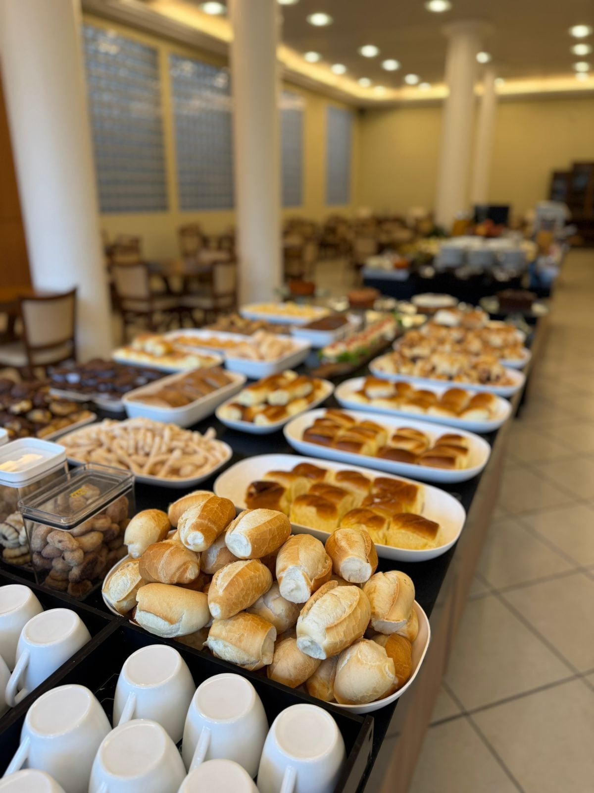 Un buffet proposant une variété de plats et des tasses blanches.