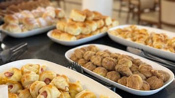 Ein reichhaltiges Buffet mit verschiedenen Speisen, darunter Gebäck und Brötchen.