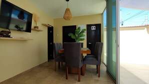 A dining area with a TV mounted on the wall, a dining table with chairs, and a potted plant. - Private Urb. in Salinas with security, few blocks from the boardwalk, WiFi, games. (Salinas)
