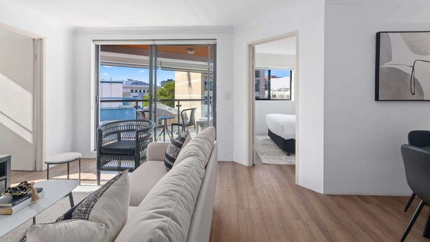 Un appartement moderne doté d’un balcon, d’un canapé, d’un coin repas et d’un lit.