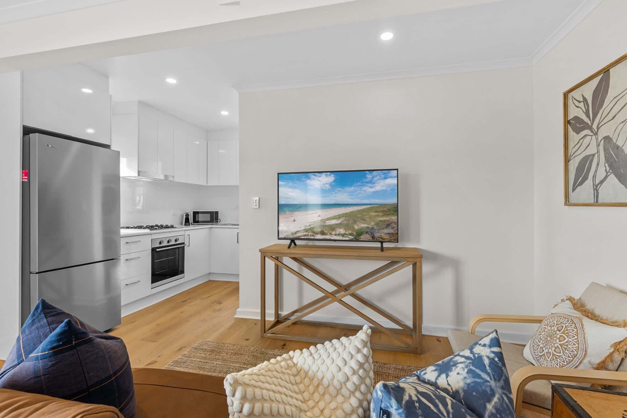 A modern kitchen with white cabinets, a stainless steel refrigerator, and a microwave.