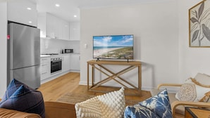 A modern kitchen with white cabinets, a stainless steel refrigerator, and a microwave.