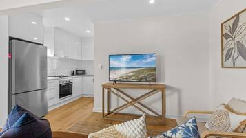 A modern kitchen with white cabinets, a stainless steel refrigerator, and a microwave.