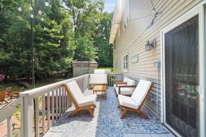 A covered patio with outdoor furniture, a wooden table, and a decorative string of lights.
