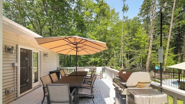 An outdoor deck with a dining table, chairs, and a grill.