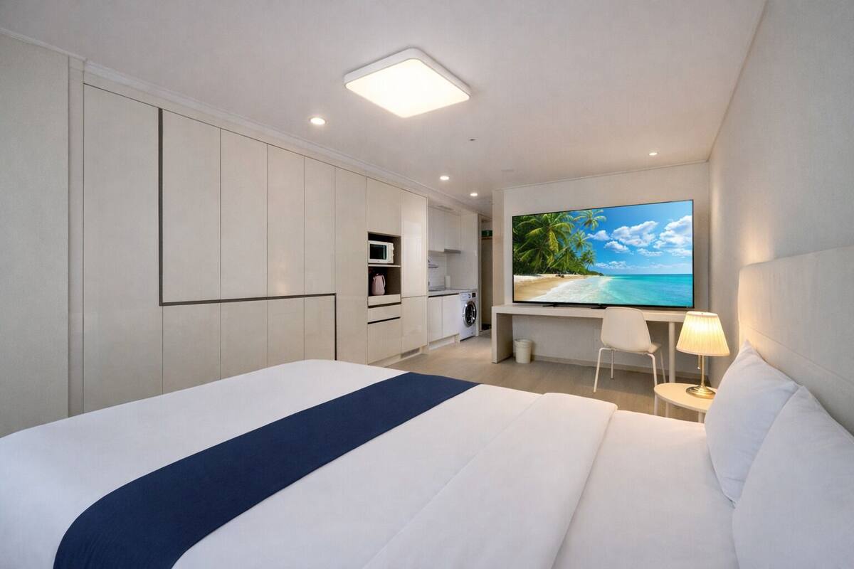 Una habitación de hotel moderna con una cama grande, un televisor de pantalla plana, un escritorio y vistas a la playa.