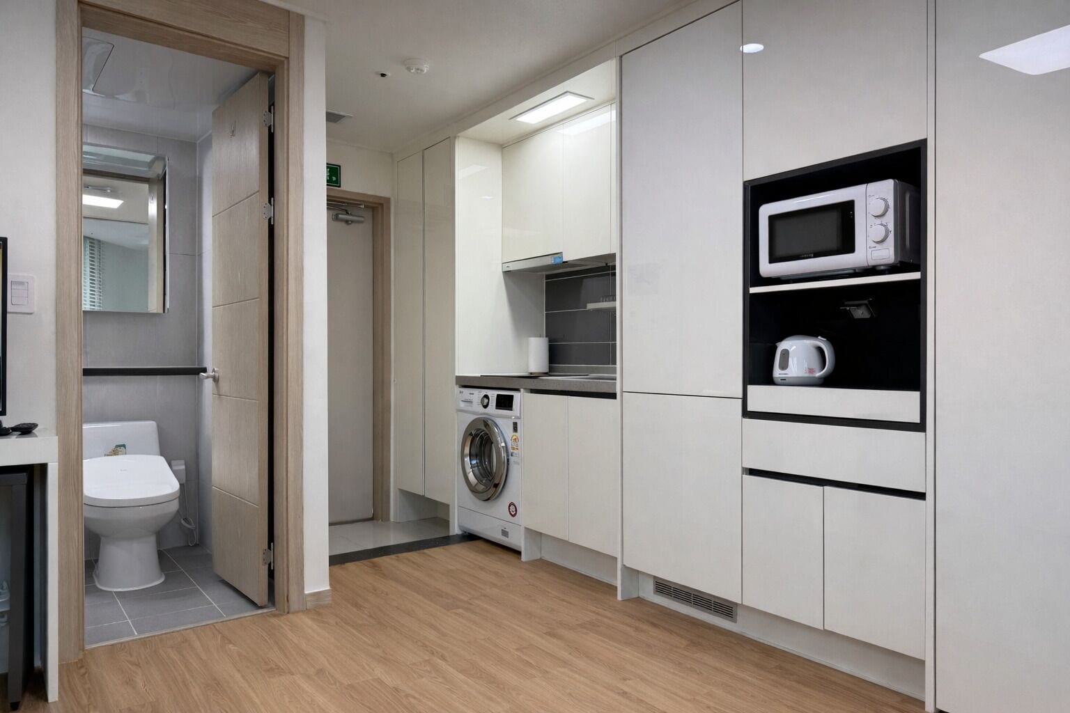 Une cuisine compacte équipée d’un four à micro-ondes, d’une bouilloire et d’un lave-linge.