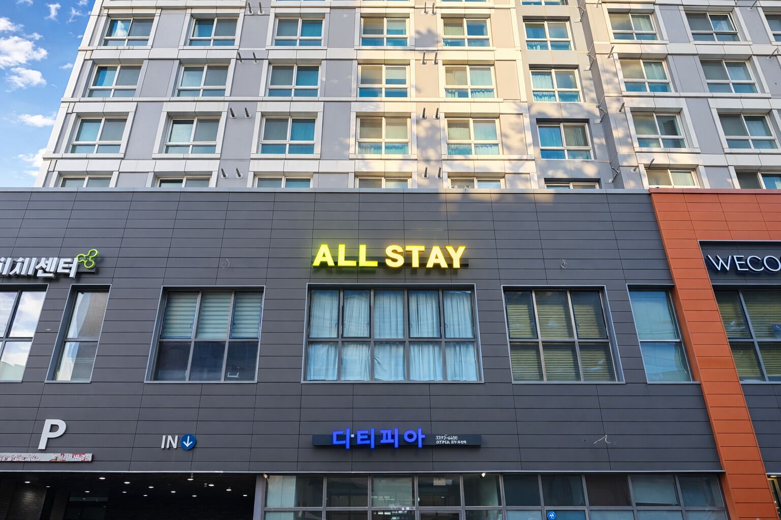 A hotel facade with "ALL STAY" signage, a parking sign, and a blue sign with Korean text.