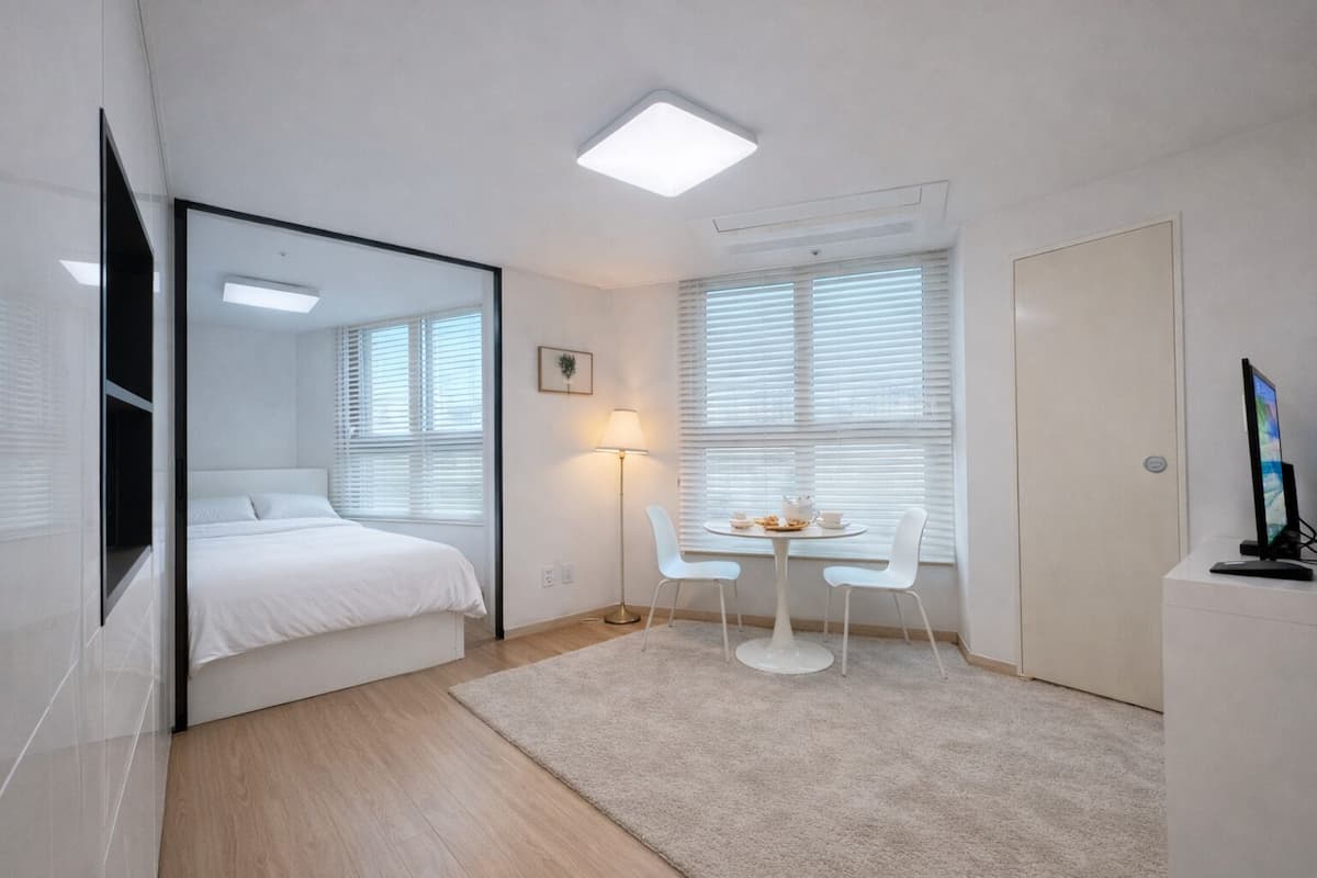 Un dormitorio moderno con cama, mesita de noche, lámpara y televisor sobre un mueble.