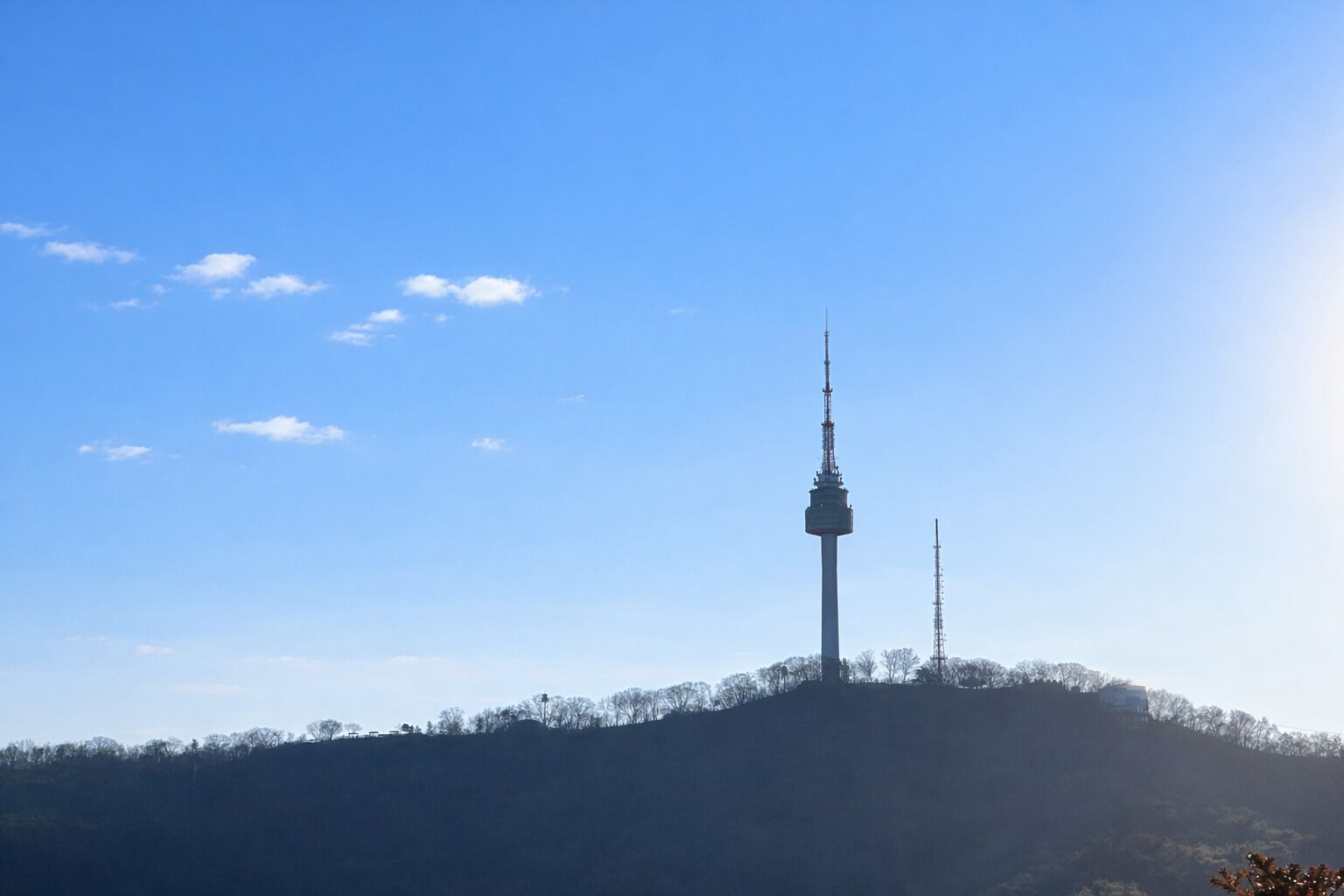 A tower on a hill with a clear sky.