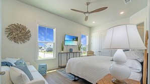 Een slaapkamer met een bed, een plafondventilator, een televisie en uitzicht op buiten.