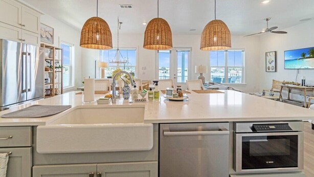 Een moderne keuken met een groot eiland, roestvrijstalen apparatuur en hanglampen.