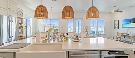 A modern kitchen with a large island, stainless steel appliances, and pendant lighting.