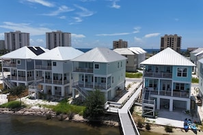Un quartier résidentiel situé sur la côte, avec des maisons à plusieurs étages dotées de balcons, un quai et une vue sur l’océan.