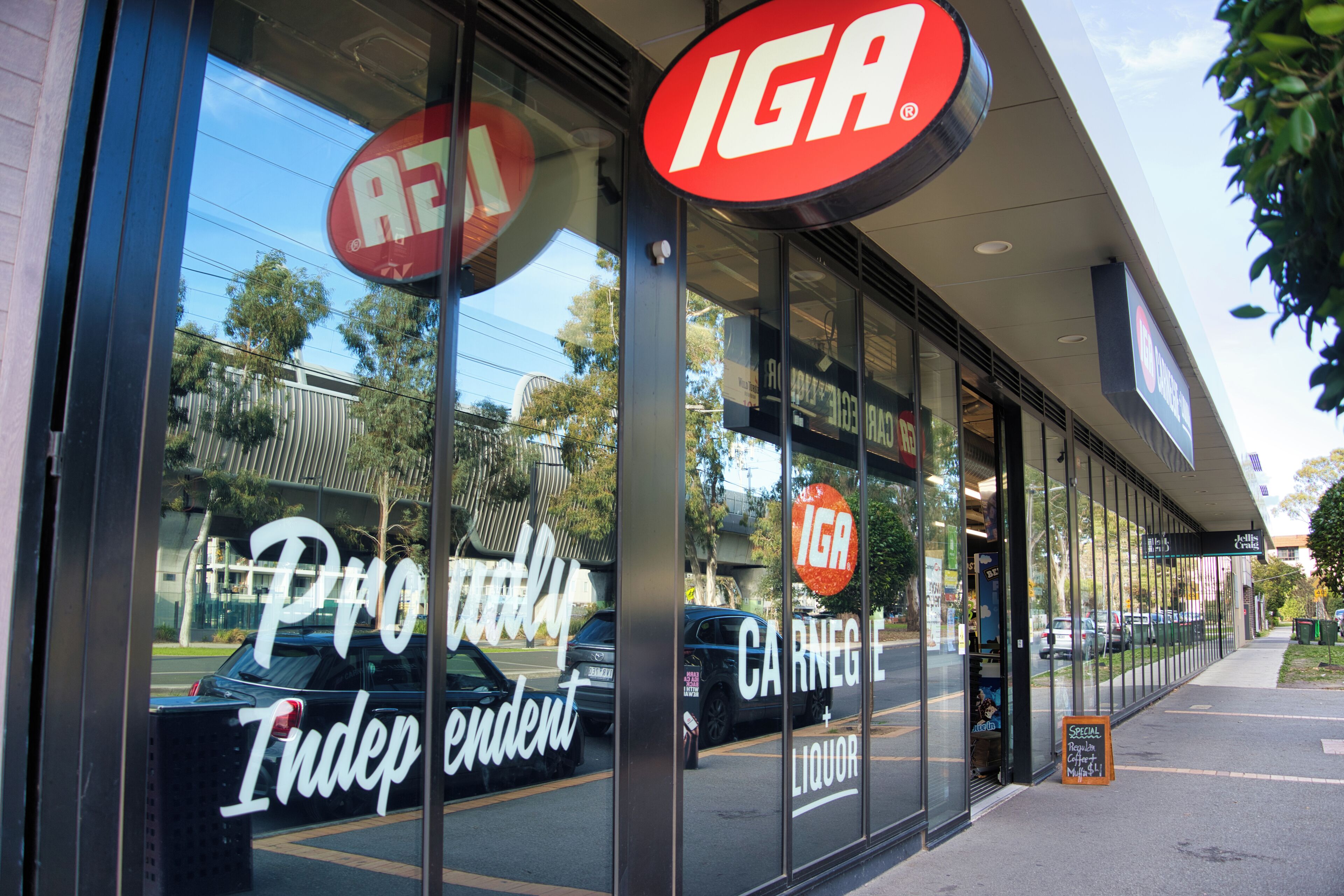 A storefront with large glass windows, a prominent red and white sign, and a reflection of a car.
