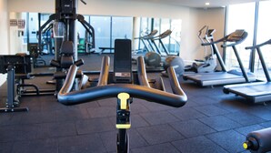Un gimnasio con equipo de ejercicio, incluyendo una bicicleta estática, cintas de correr y máquinas de pesas.