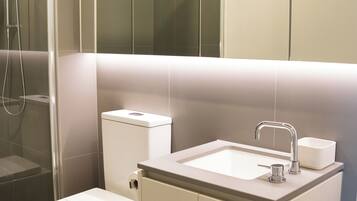 A modern bathroom with a toilet, sink, and shower.