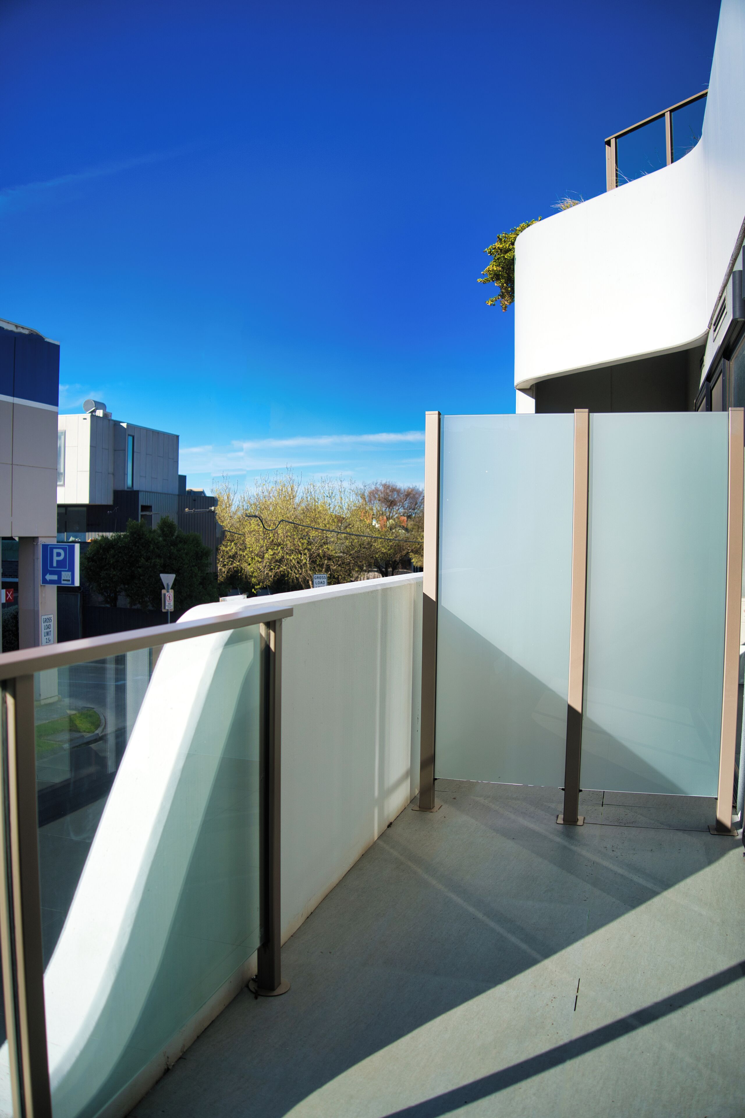 A modern building with a glass facade and a clear blue sky.
