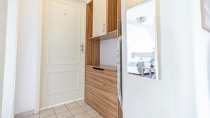 Une cuisine de taille réduite avec une porte blanche, des placards en bois et un réfrigérateur encastré.