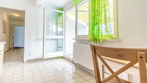 Une pièce avec une grande fenêtre, un radiateur et une chaise en bois.