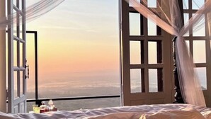 A bedroom with a large window, a bed, and a bedside table with a bottle and glasses. - 4000Dao-A Hilltop Hideaway Experience  (Mae Chan)