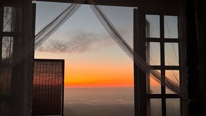 A bedroom with a large window overlooking a cityscape at sunset. - 4000Dao-A Hilltop Hideaway Experience  (Mae Chan)