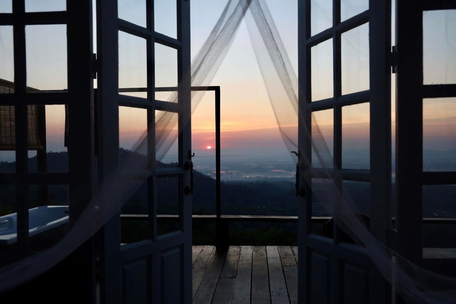 An open doorway with a view of a sunset over a landscape.