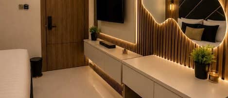 Un dormitorio moderno con una cama grande, una mesita de noche, un espejo y un televisor.