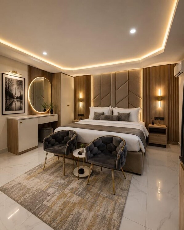 A modern bedroom with a large bed, two armchairs, a desk, and a mirror. - Villa Palazzo Hotel 2.0 (Lagos)