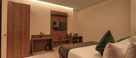 A modern bedroom with a bed, wooden wardrobe, TV, and a small desk.