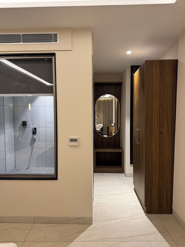 A modern bathroom with a shower, a vanity with a mirror, and a wooden wardrobe. - RC Dream Place (Greater Noida)