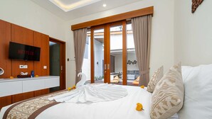 Een hotelkamer met een bed, een aan een houten paneel bevestigde televisie en een uitzicht buiten door een glazen deur.