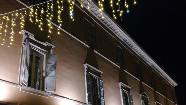 Un bâtiment doté de nombreuses fenêtres et d’un balcon, décoré de guirlandes lumineuses.