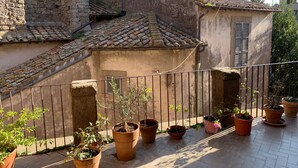 Une cour intérieure avec un mur en pierre, un toit en tuiles et des plantes en pot.