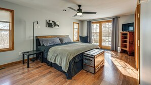 Ein Schlafzimmer mit Bett, Schreibtisch, Deckenventilator und großem Fenster.