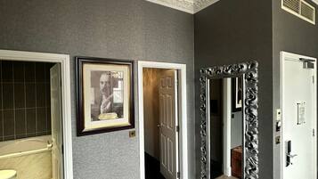 A hallway with a wooden chest, framed pictures, and a mirror with an ornate frame.