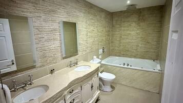 Un baño con dos lavamanos, inodoro y bañera.