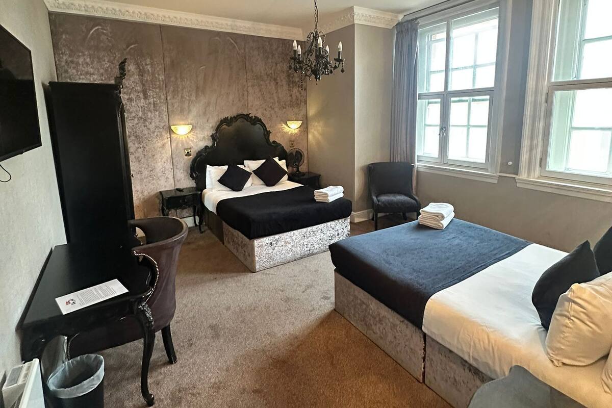 Habitación de hotel con cama, escritorio, silla, una mesita y ventana.
