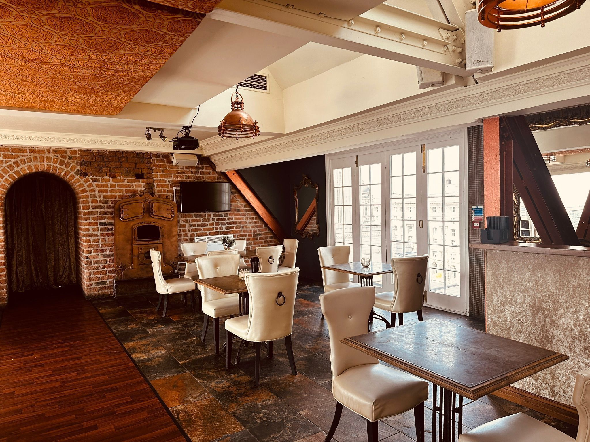 A restaurant with brick walls, wooden flooring, and white chairs.