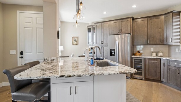 A kitchen with a marble island, stainless steel appliances, and wooden cabinets.