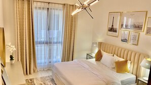 Een moderne slaapkamer met een groot bed, nachtkastje, lamp en uitzicht op de Eiffeltoren door dunne gordijnen.