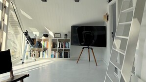 Une pièce équipée d’un télescope, d’un téléviseur à écran plat et d’une bibliothèque.
