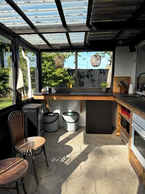 A modern kitchen with a wooden countertop, a built-in oven, and a large window overlooking a garden. - Lovely year-round home with sea view (Føllenslev)