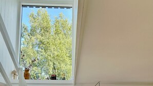 Une pièce avec un escalier, un canapé et deux fenêtres donnant sur des arbres.