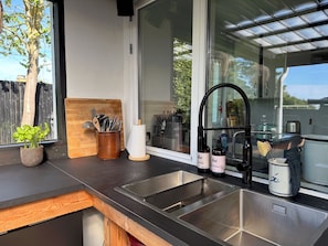 A kitchen with a large window, a wooden cutting board, a knife holder, and a sink.