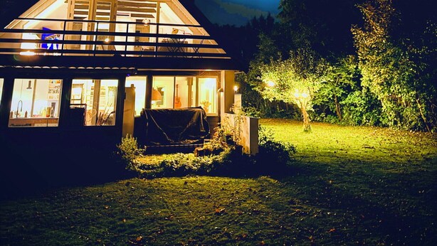 Une maison avec un toit triangulaire, de grandes fenêtres et un intérieur visible.