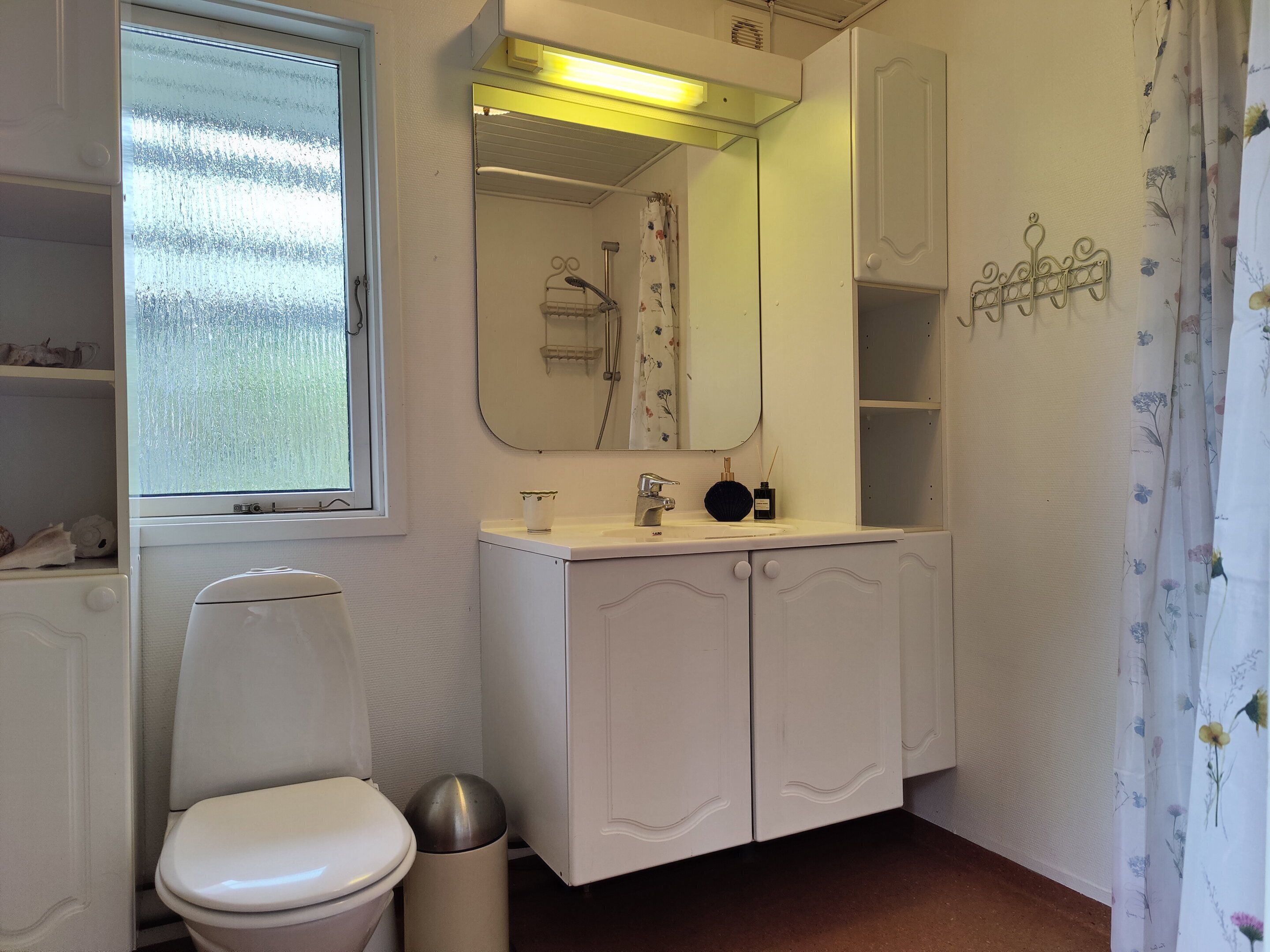 Ein Badezimmer mit Toilette, Waschbecken, Spiegel und Dusche.