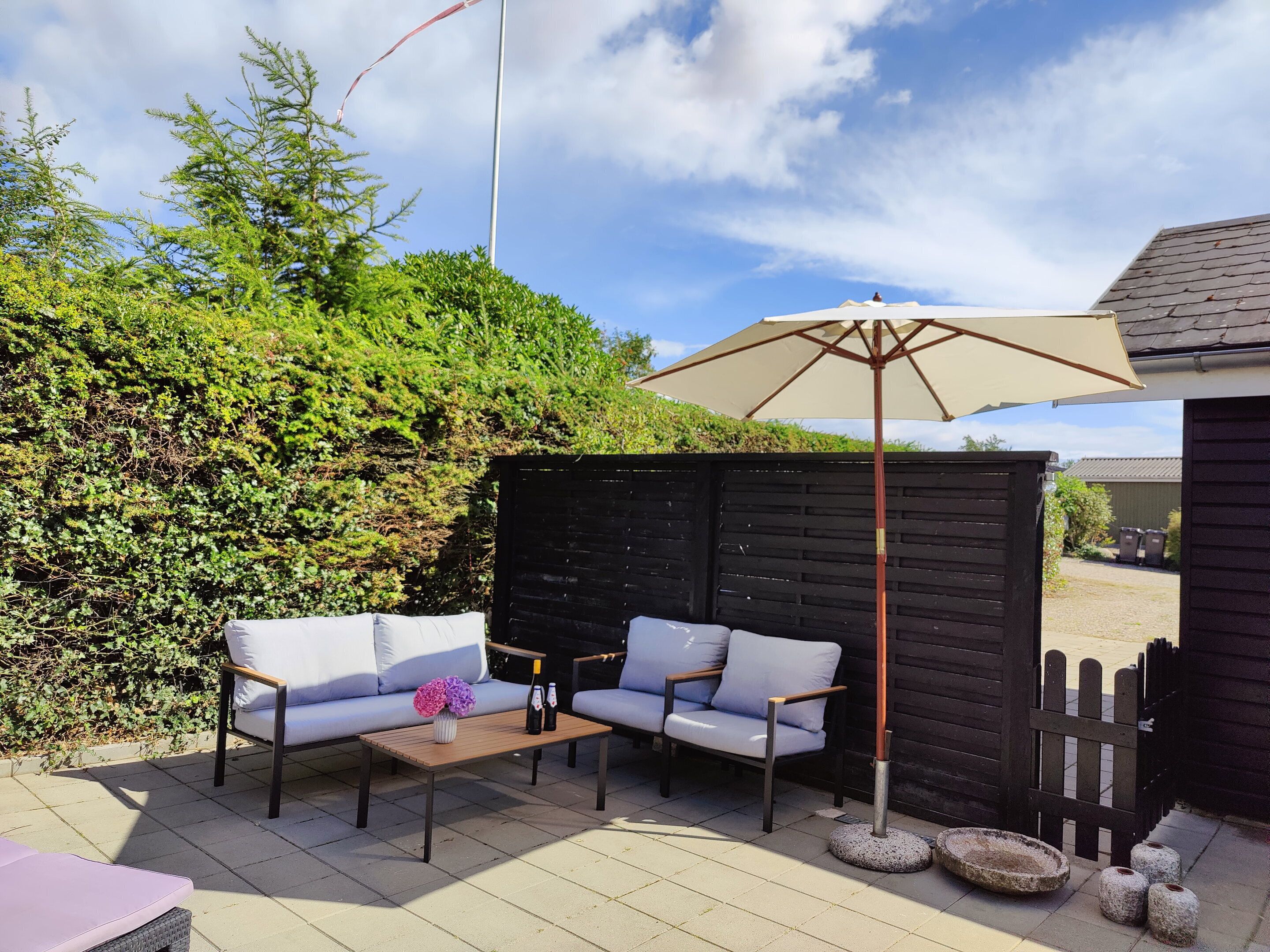 An outdoor patio with a sofa, a table, and a large umbrella.
